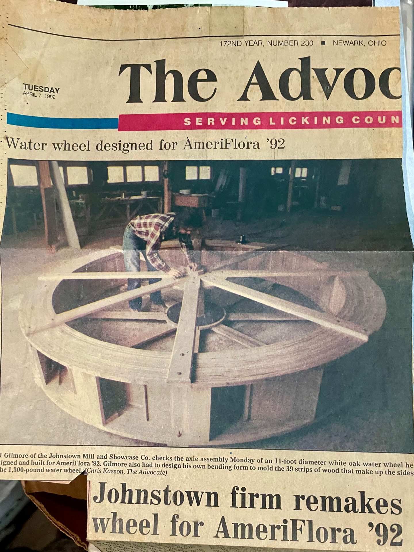 Newspaper clipping: Bill Gilmore checking the axle assembly of the 11-foot white oak water wheel built for AmeriFlora '92