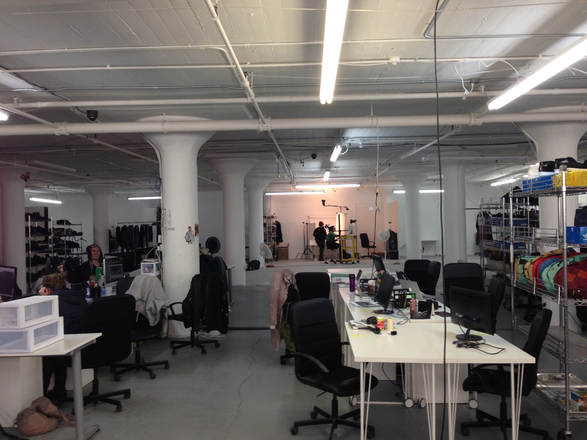 The studio bullpen with desks, wardrobe racks and a shoot in progress