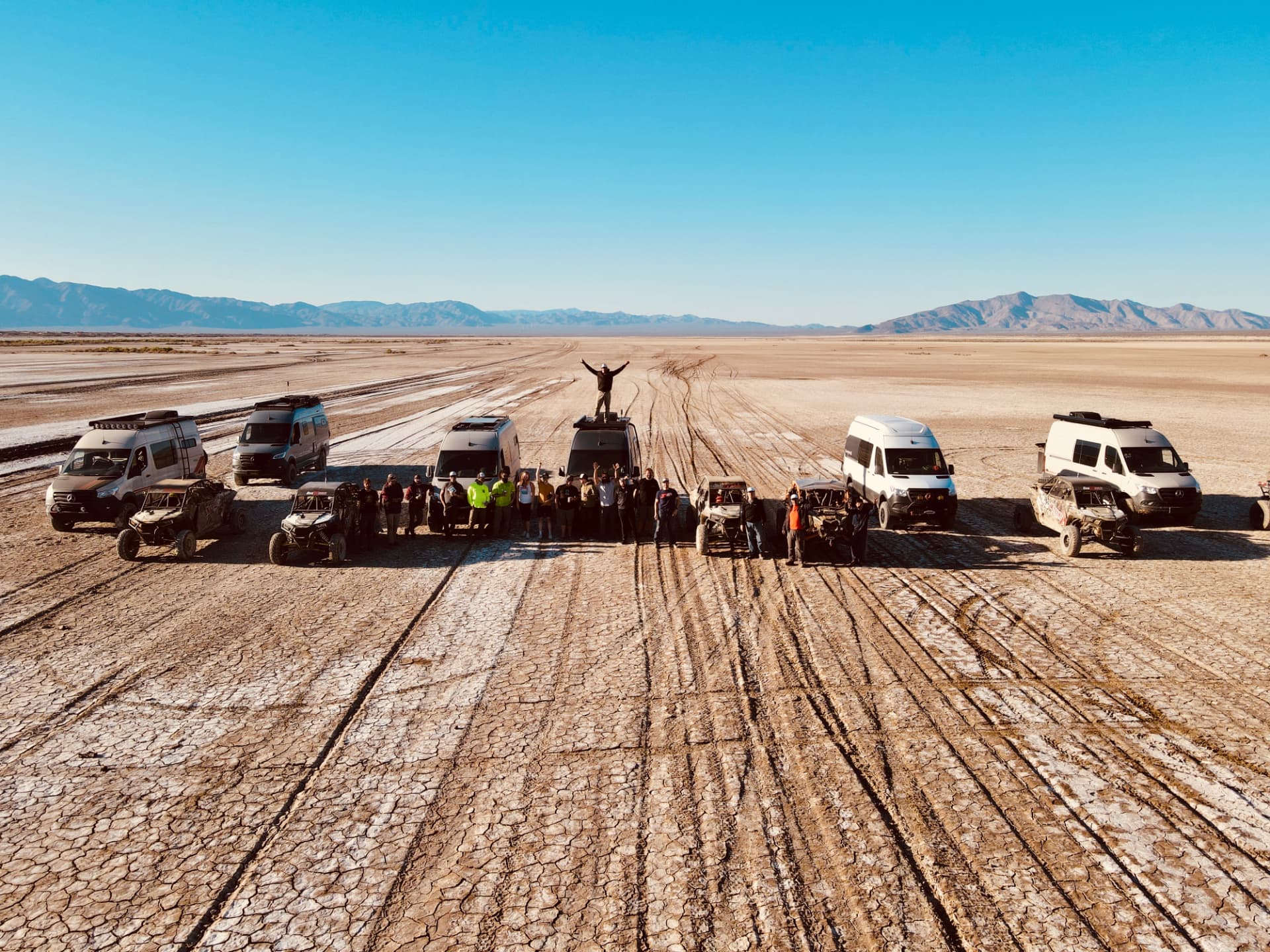 A convoy of adventure vans lined up in a dry lake bed in Baja California